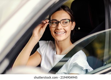 A Nerdy Girl Sitting In Her Car And Looking For A Parking Spot. A Girl In A Car