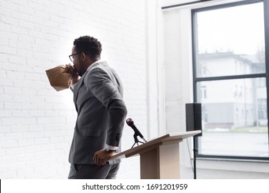 nervous african american speaker breathing with paper bag and having panic attack during business conference in office