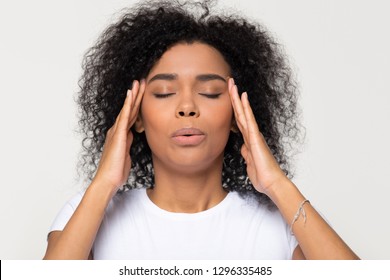 Nervous African Woman Breathing Calming Down Relieving Headache Or Managing Stress, Black Girl Feeling Stressed Self-soothing Massaging Temples Exhaling Isolated On White Grey Studio Blank Background