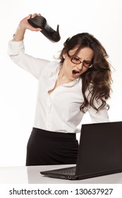 nervous and angry business woman destroys her laptop with high heels