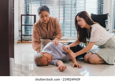 nervous Asian woman granddaughter and wife shaking her grandfather trying to awake him. the old man loses conscious falling on the floor in living room at home. senior man fallen from wheelchair. - Shutterstock ID 2198249439