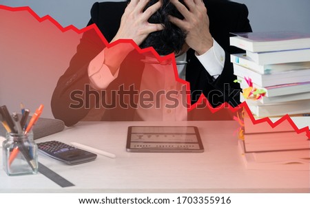 a nervous business man in desk when business crash with red stock price chart plummet, slow growth economy