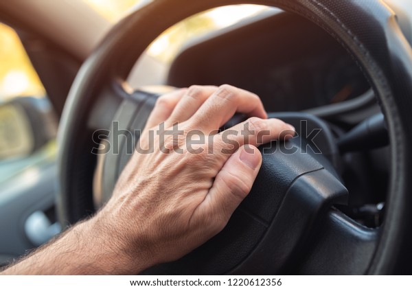 Nervous driver\
pushing car horn on steering\
wheel