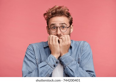 Nervous embarassed man bites nails, looks worried before visiting doctor or dentist. Anxious concerned male student feels anxiety before passing course or diploma paper, afraid of difficult questions - Powered by Shutterstock