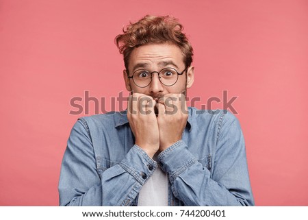 Nervous embarassed man bites nails, looks worried before visiting doctor or dentist. Anxious concerned male student feels anxiety before passing course or diploma paper, afraid of difficult questions