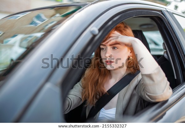 Nervous female driver sits at wheel, has
worried expression as afraids to drive car by herself for first
time. Frightened woman has car accident on road. People, driving,
problems with transport
