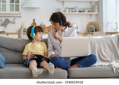 Nervous Freelancer Mother Sitting On Couch At Home Office During Lockdown, Working On Laptop, Asks Not To Make Noise. Little Child Distracts From Work, Showing Tablet, Asking Attention From Busy Mom. 