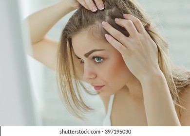 nervous girl looking in the mirror her scalp