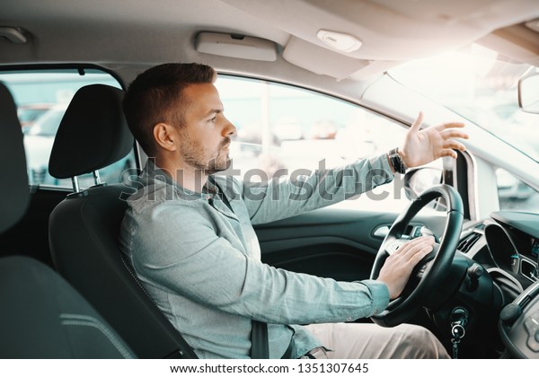 Nervous handsome Caucasian man getting stacked in\
traffic while driving his\
car.