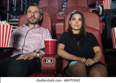 Nervous Looking Couple Sitting Next To Each Other At The Movie Theater On Their First Date