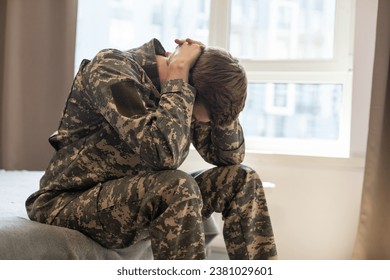 Nervous male military suffering depression, sitting alone at home, PTSD concept.