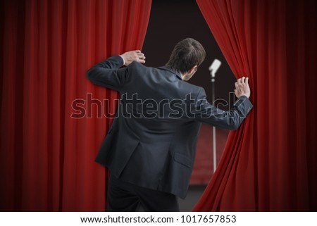 Nervous man is afraid of public speech and is hiding behind curtain.