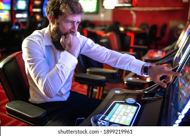 A Nervous Man In A White Shirt Sits Behind A Vending Machine And Nervously Bites His Fist Because He Has No Luck In Gambling