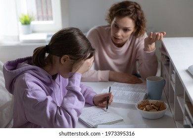 Nervous mother explaining educational material to stressed unhappy young adolescent kid, scolding lazy daughter for bad results, feeling dissatisfied with wrong done task, arguing disciplining at home - Powered by Shutterstock