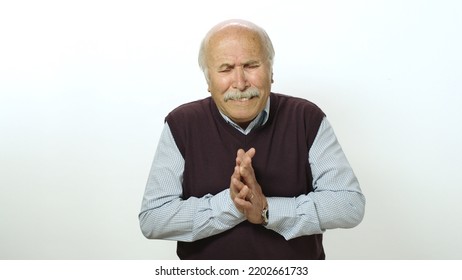 Nervous Old Man Is Very Scared. Studio Portrait Of Old Man Isolated On White Background. The Old Man Feels Anxious And Fearful Tension, Covers His Face With His Hands.