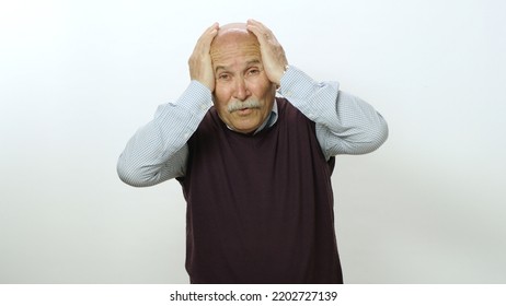 Nervous Old Man Is Very Scared. Studio Portrait Of Old Man Isolated On White Background. The Old Man Feels Anxious And Fearful Tension, Covers His Face With His Hands.