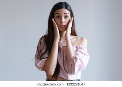 Nervous Pretty Caucasian Girl Holding Hands Near Face. Young Female Student In Light Pink Top Looking In The Mirror And Checking Make Up. First Date Concept