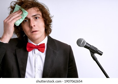 Nervous And Shy Caucasian Public Speaker With Microphone, Student Is Afraid Of Giving Speech For Crowd Of People Or Audience. Sweaty Face, Man Holding Mic. Bad Presentation