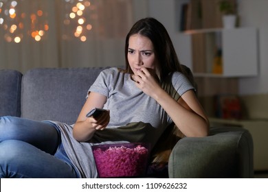 Nervous Spectator Watching Tv At Home In The Night Sitting On A Couch In The Living Room