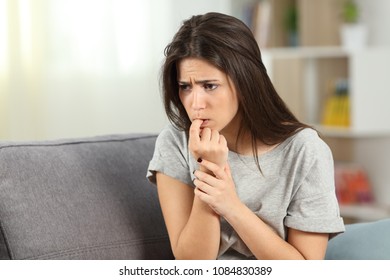 Nervous Teen Biting Nails Alone Sitting On A Couch In The Living Room At Home