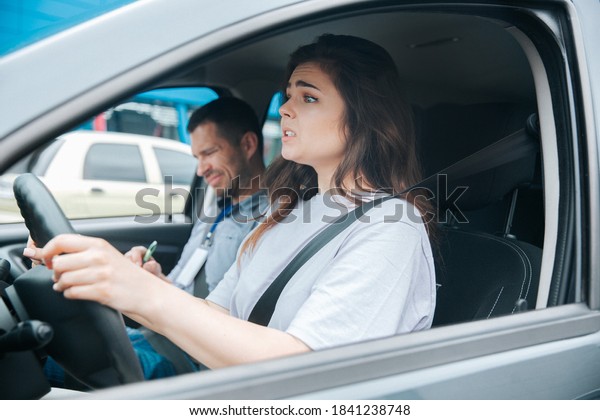 Nervous\
upset woman can\'t take driving exam. Car accident during driving\
lesson concept. Usatisfied male instructor notices something bad in\
his paper. Failed driving license exam\
concept.
