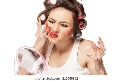 nervous woman with curlers removes makeup with her hands