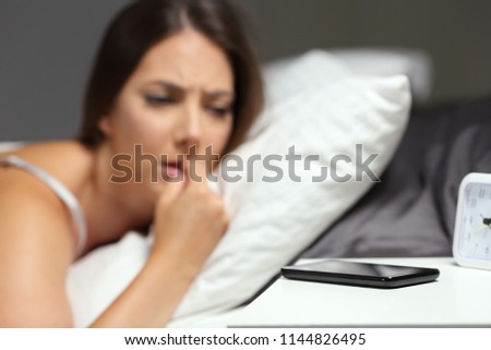 Nervous woman waiting for a phone call on a bed in the night