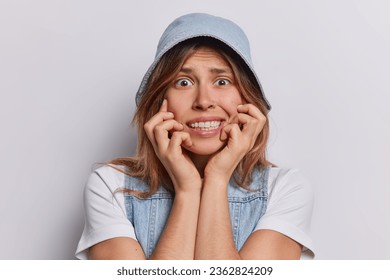 Nervous young woman looking guilty or worried being scared of something wears denim panama casual t shirt and vest isolated over white background. People reactions and negative emotions concept