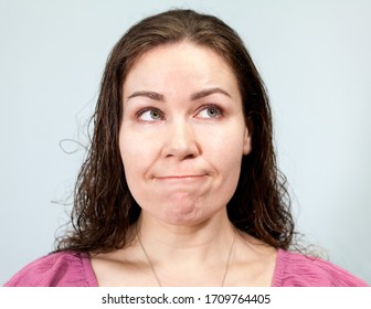 Nervousness And Anxiety, Pursed Lips And A Look To The Side, Portrait Of Woman On Grey Background, Emotions Series