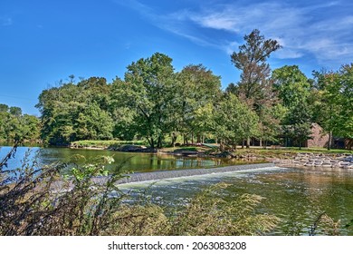 Neshaminy Creek In Tyler State Park In Bucks County,Pennsylvania USA. With A Small Waterfalls And Colorful Docked Canoes. A Beautiful Blue Sky. 