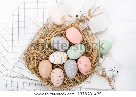 Nest with Easter eggs on a white wooden background, top view with copy space