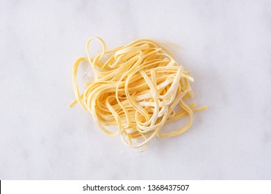 Nest Of Fresh Linguine Pasta, Top View Against A White Marble Background