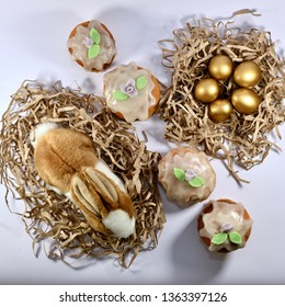 A nest with a plush hare and a nest with painted eggs separated by Easter cakes, arranged in a row diagonally. - Powered by Shutterstock