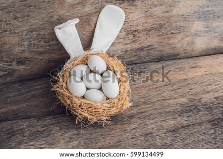 A nest with three white Easter eggs and bunny ears at home on Easter day. Celebrating Easter at spring. Painting eggs.