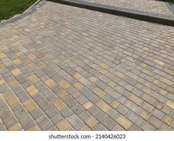 Nested pavers of various colors, around the grass is green, chic garden