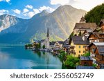 Nestled between majestic mountains, Hallstatt Austriashowcases its charming architecture along the tranquil lake, reflecting golden sunlight as the day draws to a close. A captivating moment awaits.