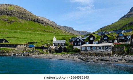 Nestled between towering cliffs, the quaint Bour Village showcases traditional wooden houses and a charming white church. Crystal-clear waters allure visitors, creating a serene landscape.