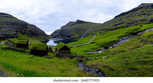 Nestled between towering cliffs, this captivating location in the Faroe Islands features traditional grass-roofed houses surrounded by vibrant green hills and a serene lake. Saksun village