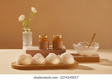 Bird’s nests placed on wooden dish, empty label jars on brown podium, and a bowl with bird’s nest soup and a spoon inside. This is a high-class dish, beneficial for the elderly people and children