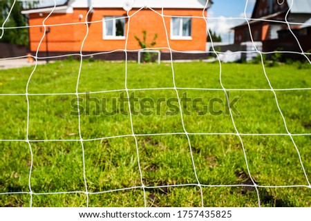 Net of football goal on the green lawn grass on a plot near the house. Family play