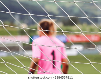 The net of a goal through which the goalkeeper of a women's football match is seen - Powered by Shutterstock