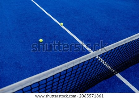 Net and serving lines of a blue paddle tennis court