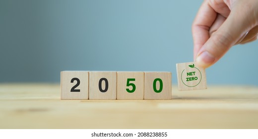 Net zero by 2050. Carbon neutral. Net zero greenhouse gas emissions target. Climate neutral long term strategy. No toxic gases. Hand puts wooden cubes with net zero icon in 2050 on grey background. - Shutterstock ID 2088238855