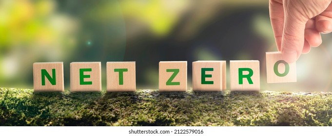 Net zero by 2050 Carbon neutral. Net zero greenhouse gas emissions target. Climate neutral long strategy. No toxic gases. Hand puts wooden cubes with netzero icon in green background. - Shutterstock ID 2122579016