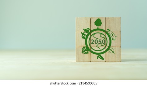 Net zero by 2050. Carbon neutral. Net zero greenhouse gas emissions target. Decarbonization long term strategy. No toxic gases. Hand puts wooden cubes with net zero icon in 2050 on grey background. - Shutterstock ID 2134530835