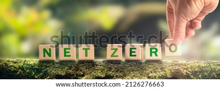 Net zero by 2050 Carbon neutral. Net zero greenhouse gas emissions target. Climate neutral long strategy. No toxic gases. Hand puts wooden cubes with netzero icon in green background panoramic