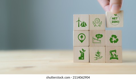 Net zero and carbon neutral concept. Net zero greenhouse gas emissions target. Climate neutral long term strategy. Hand put wooden cubes with green net zero icon and green icon on grey background. - Shutterstock ID 2114062904