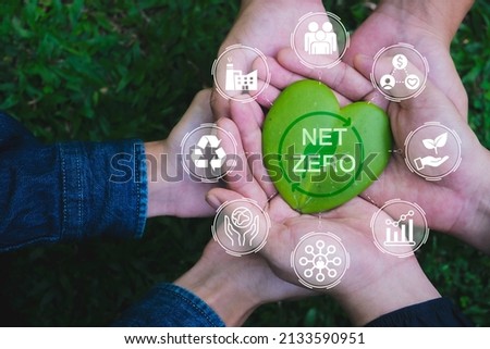 Net zero and carbon neutral concept. Hands adult Teamwork harmony Holding heart leaf on hands with green net zero icon and green icon. Net zero greenhouse gas emissions target.