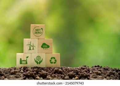 Net zero and carbon neutral concept.wooden cubes with netzero icons - renewable energy, co2 emissions reduction, green production, waste recycling.in green background  