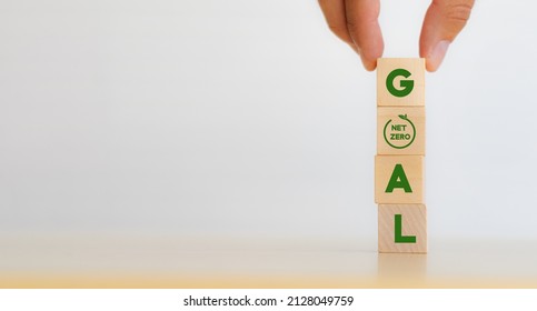 Net Zero Goal And Strategy Concept. Decarbonization, Low Carbon Economy For Sustainable Development. Hand Put Vertical Wooden Cubes With “GOAL” Text And Net Zero Icon On White Background ,copy Space